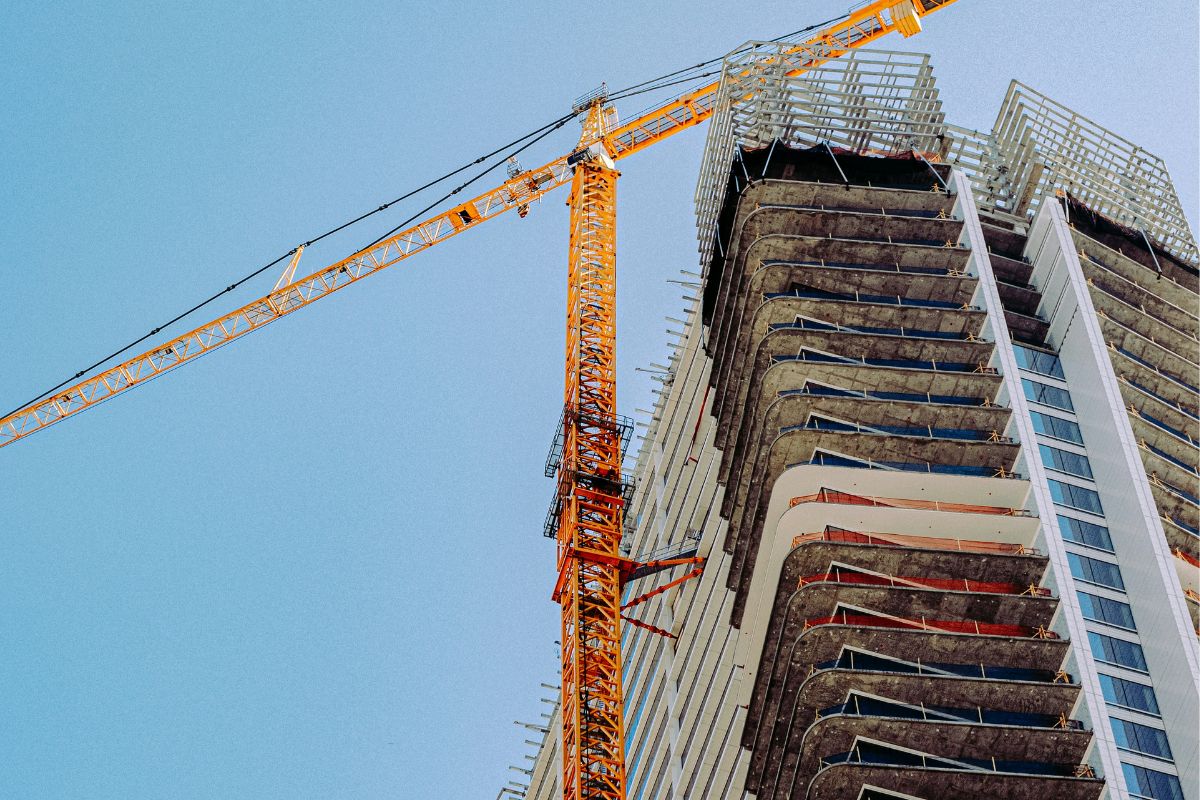 Crane and high-rise building under construction against a clear blue sky.