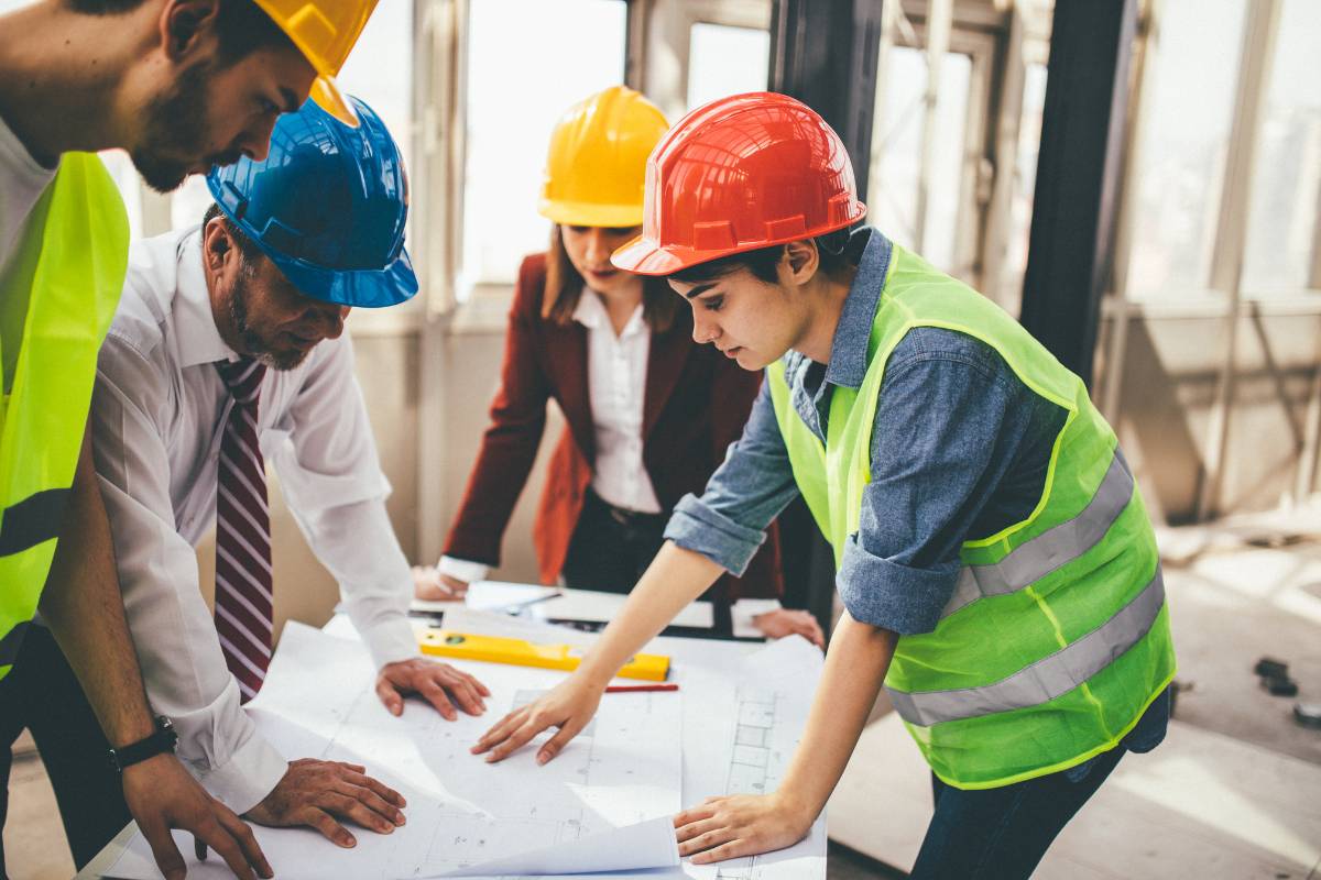 Several construction workers around a table at an outdoor location