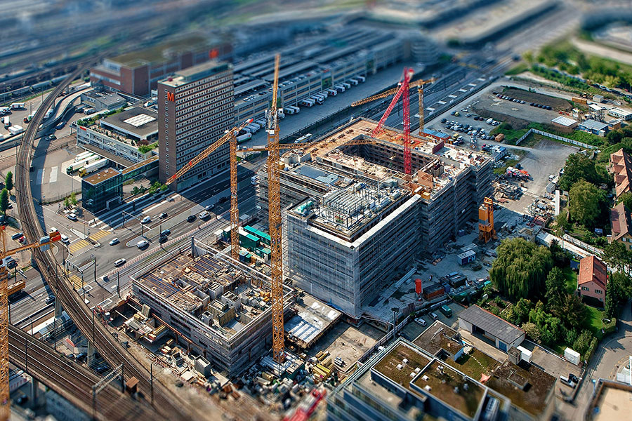 aerial view of commercial building construction site with cranes and machinery