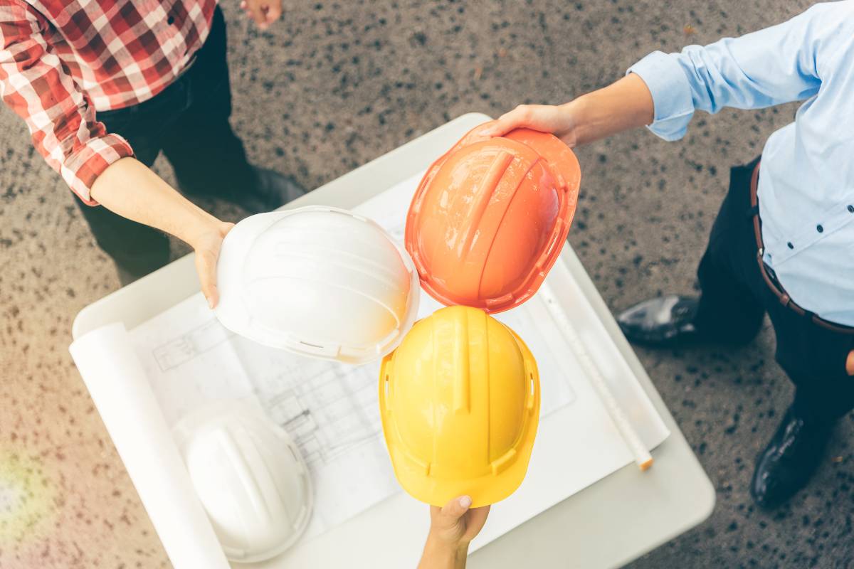 3 construction workers holding construction hard hats
