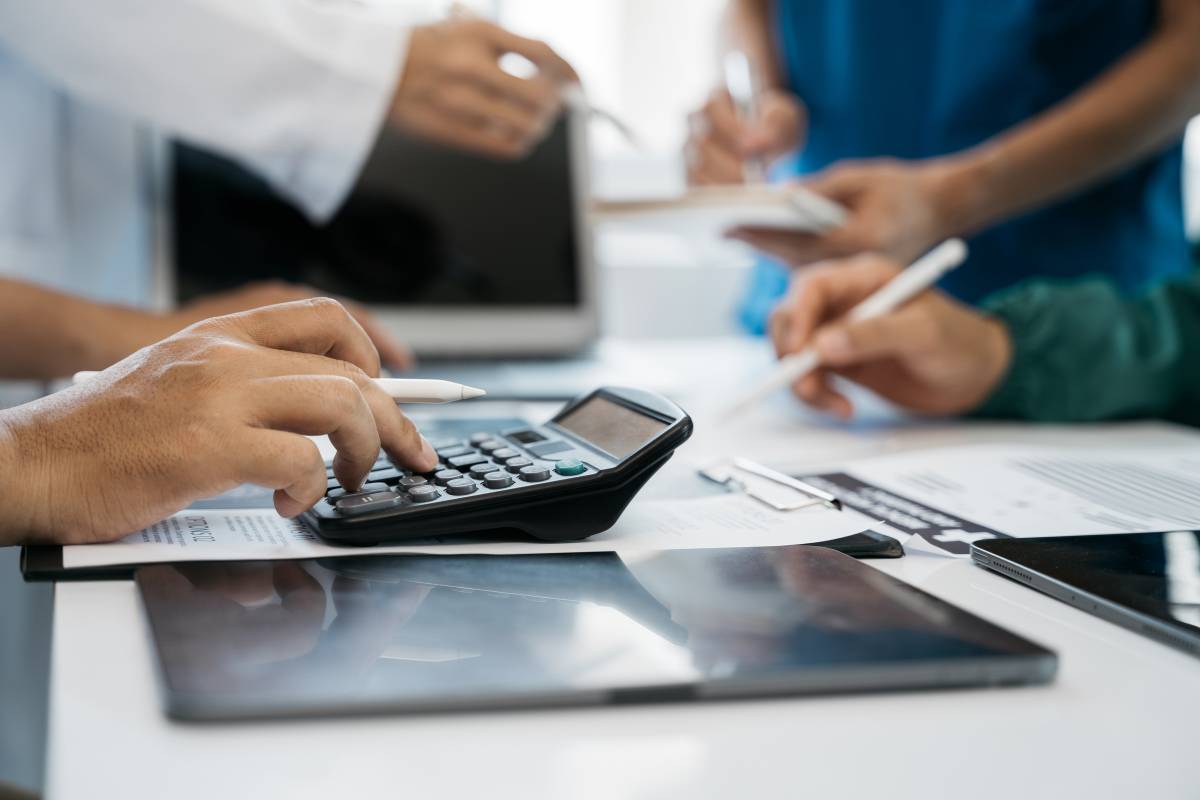 Man using a calculator next to a tablet