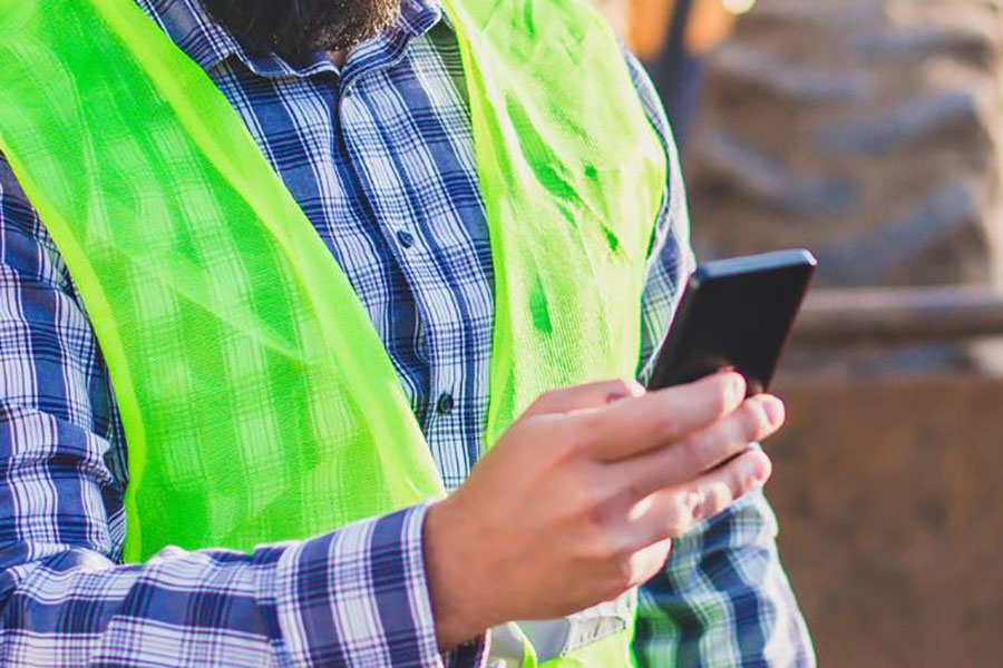 construction worker looking at mobile device in the field