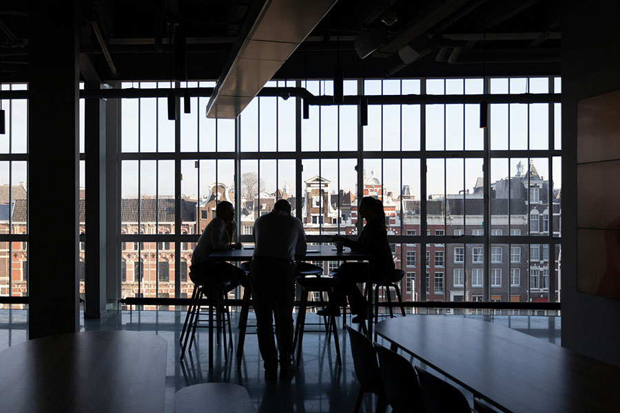 three colleagues gathered around a high top table in an architectural steel office space