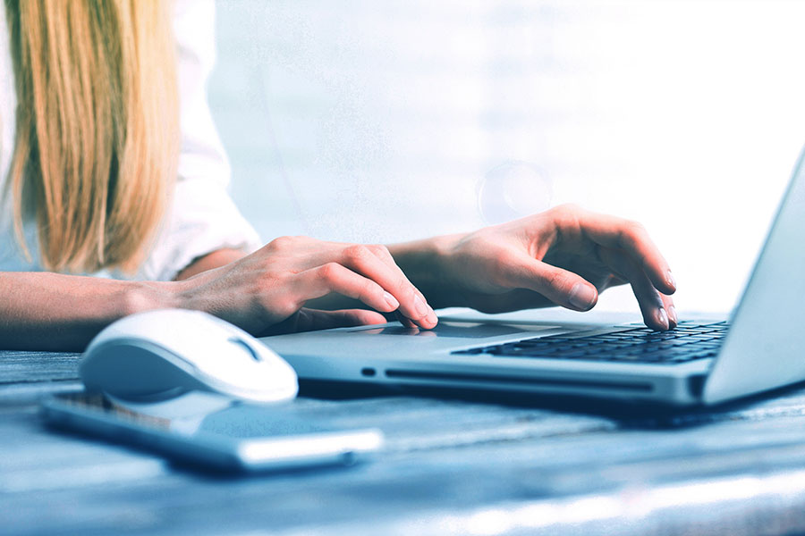 a person's hands typing at a laptop