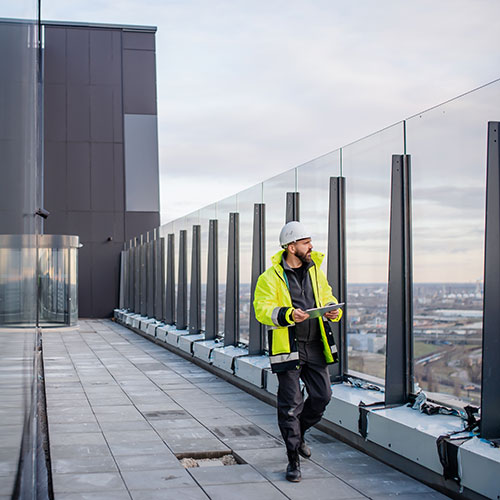 Man walking on rooftop wearing a high vis jacket